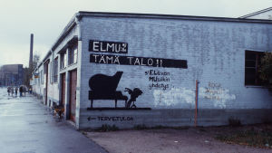Graffiti "Elmulle tämä talo" Lepakkoluolan päädyssä