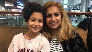Yasmin med sin dotter Bianca mor och dotter ler in i kameran på flygplats