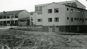 Under årens lopp har det gjorts ändringar och byggts till på yrkesskolan. Här är den år 1969. Svartvit bild av Västra Nylands ykesskola, en vit stenbyggnad, från 1969.