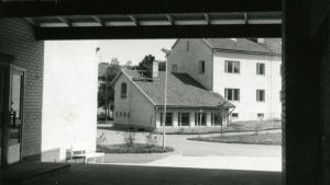 Skolbyggnaden blev klar år 1952. Fotot är från 1969. Svartvit bild av Västra Nylands ykesskola, en vit stenbyggnad, från 1969.