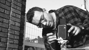Mies joka kuvasi New Yorkin Valokuvaaja Harold Feinstein säätää kameraansa kadulla New Yorkissa