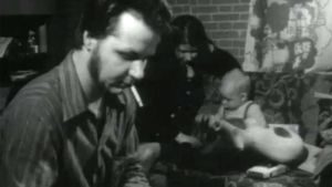 Mies, nainen ja lapsi pienessä huoneessa asumisen ahtaudesta kertovassa ohjelmassa (1970-luku)