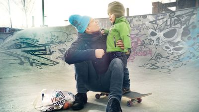 En pappa håller om sin pojke vid en skejtramp.