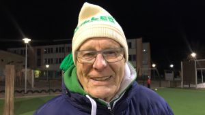 Åke Kullas fina Akilles-mössa är från 1985. Han har varit aktiv inom Akilles bandy sedan 1982! En äldre man står utomhus framför en idrottsplan. Han har på sig en mössa som det står Akilles på.