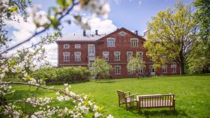 Ett av husen som öppnar sina dörrar är det här tegelhuset från 1899. Huset ligger i Billnäs på Bagarvägen 2. Ett rött gammalt tegelhus. I förgrunden syns äppelblom och en gräsmatta med en bänk och ett bord.