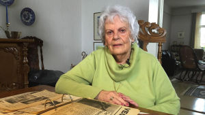 Scoutingen har varit en del av Atti Winters liv under 47 års tid. Dam sitter vid matsalsbord, bläddrar i gamla tidningsklipp.