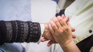 Vårdare håller patients hand. 