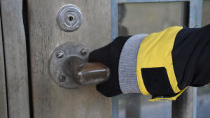 Henkilön käsi ovenkahvassa.