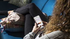Nuori suomalainen nainen istuu sohvalla ja käyttää Snapchattia.