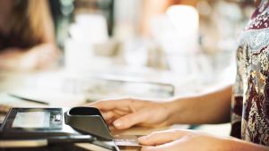 Nainen asettaa luottokorttia maksupäätteeseen.