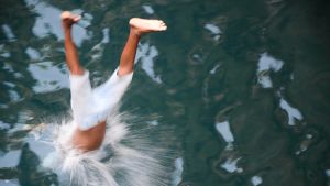 Poika sukeltaa mereen pää edellä.