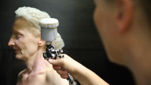 Nainen suihkuttaa toista naista suihkurusketussumuttimella