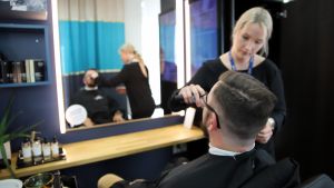 Partamuotoilija siistii asiakkaansa partaa.