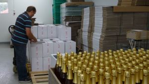 Mies seisoo pakkaamossa pullolaatikoiden äärellä.