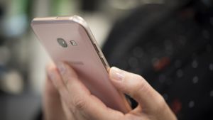 Nainen puhelin kädessä.