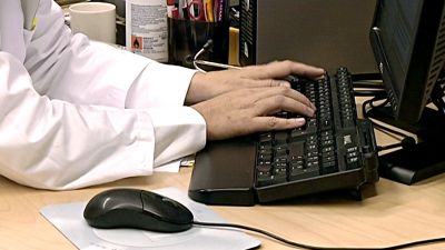 Läkare skriver något på ett tangentbord.