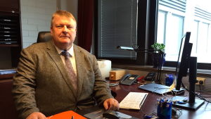 Finansminister Mats Perämaa ser positivt på försäljningen. En person (Mats Perämaa) sitter vid ett skrivbord.