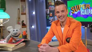 Plåstret och Jontti Programledaren Jontti granbacka sitter vid ett skrivborde i tv-studion tillsammans med tv-musen Plåstret