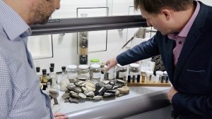 Kalle Pirk visar ett spännande skåp där det finns alla möjliga sorters oljeskifferstenar, vätskor utvunna ur oljeskiffer och annat relaterat till branschen. En man visar ett laboratorieskåp fullt med stenar och provrör.