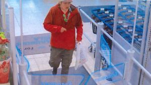 En man i röd blus och skärmmössa som går i en mataffär. Polisens foto på en misstänkt rånare i Karis.