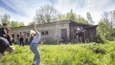 Människor dansar på en äng och i bakgrunden spelar en man musik.