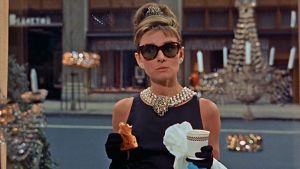 Audrey Hepburn syö aamiaistaan kultasepänliike Tiffanyn näyteikkunan ääressä elokuvassa Aamiainen Tiffanylla