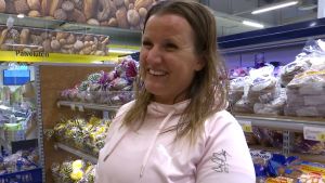 Susanna Virtanen En kvinna som ler framför en bröddisk i en matbutik.