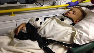 Adam på väg mot en lång sjukhusvistelse i Tammerfors. adam nyholm ligger i ambulansen. han har en filt på sig och ett kramdjur i famnen.
