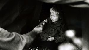 Ruotsiin saapuneiden evakoiden odotusta teltassa. Poikalapsi syö karamellia. (1942)