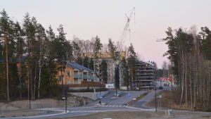 Bostäder byggs i Söderkulla. Vy från Söderkulla där manser en stor lyftkran och ett halvfärdigt höghus på en kulle.