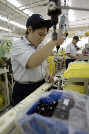 Kina är den största köparen av industrirobotar. Får hon behålla jobbet? Arbetare monterar komponenter