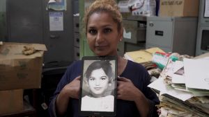 Yasmin i rummet där hon sov som barn Kvinna håller upp ett foto av sig själv som barn