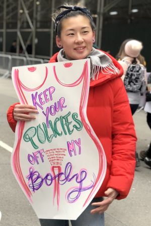 Från höstens kvinnormarsch i New York Kvinna håller upp plakat med kvinnliga former: "Håll politiken borta från min kropp"