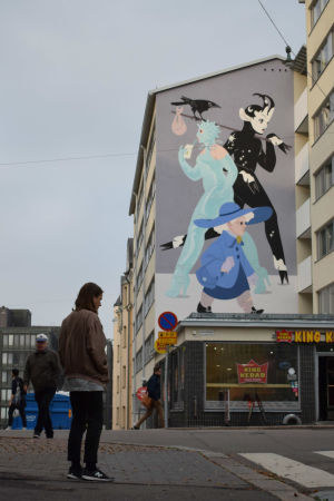 Eero Lampinen är konstnären bakom muralmålningen på Vasagatan 19 i Berghäll. En man står på gatan framför en husgavel som han har målat ett konstverk på.