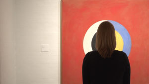 Det går runt. En museibesökare framför en tavla av Hilma af Klint. en museibesökare står framför ett verk av Hilma af Klint