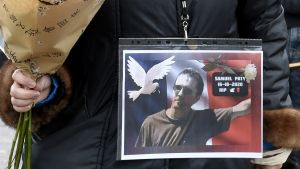 En demonstrant i Lille bär Samuel Patys bild på jackan. En kvinna håller i en blombukett och bär en bild på en man på sin jacka.