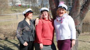 Nina Sederlöf, Julie Ebbe och Camilla Andelin. Tre kvinnor i studentmössor vid ett träd med en damm i bakgrunden.