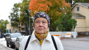 Christina Jäkkä trivs i Lovisa. En kvinna i vit jakka står ute på en gata. Bakom henne syns ett träd med orange löv.