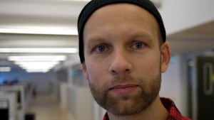 Robert Gehring på upphovsrättsorganisationen Stim en porträttbild av robert gehring i en korridor med bakgrunden ur fokus. Han bär en rutig skjorta och en mössa.