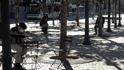 Några personer sitter i skuggan vid Avenida dos Aliados i Portos centrum.