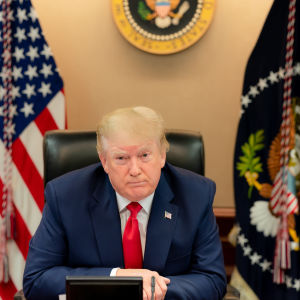 Donald Trump sa att det inte finns rum för våld och vandalism inom hans rörelse. Donald Trump seuraa videoneuvottelua G20 kokouksessa. Taustalla USA:m ja USA:n presidentin liput.