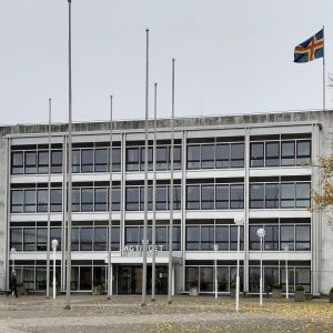Lagtingets fasad i Mariehamn väntar på nya politiker i november. Lagtingets marmorhus i Mariehamn i höstregn, med Ålands flagga på taket