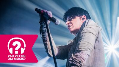 Gary Numan sjunger och håller i en mikrofon som är i en mikrofonställning.