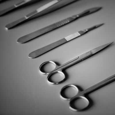 Sairaalan leikkaussalissa käytettäviä saksia ja veitsiä pöydällä vierekkäin.