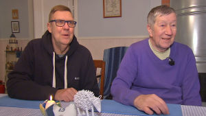 Anders Ginlund och Pertti Metso bor i sitt barndomshem. De är stolta över att ha blivit utnämda till Kimitoöns lokalkändisar. Två män sitter vid ett matbord.