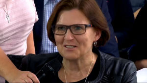 Maria Palm. Skärmdump från Svenska Yles livestream från diskussionen i Nyrkarleby. En kvinna med mikrofon framför sig.