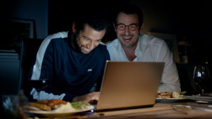 Christian (Claes Bang) och hans kollega Michael (Christoffer Læssøe) sitter vid en laptop och skrattar.
