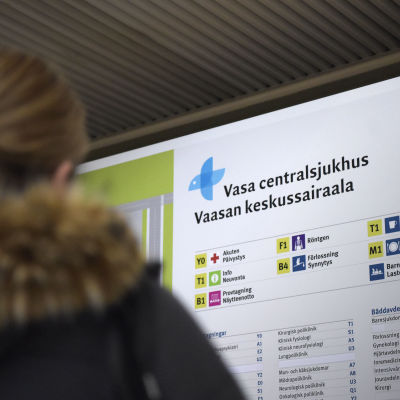 en infoskylt över Vasa Centralsjukhus med en kvinna i förgrunden