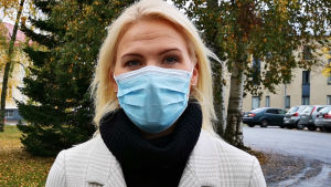 Marina Kinnunen säger att coronasamordningsgruppen om en vecka ska ta ställning till om man kan lätta rekommdendationerna eller inte. Tills dess gäller tio personer som får samlas, använd munskydd och håll två meters avstånd. Arkivbild. En kvinna med långt ljust hår och rutig kappa står i ett höstigt landskap och har ett munskydd i ansiktet.