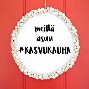 Punaisessa ovessa roikkuu kranssi, minkä keskellä teksti: "meillä asuu #kasvurauha"